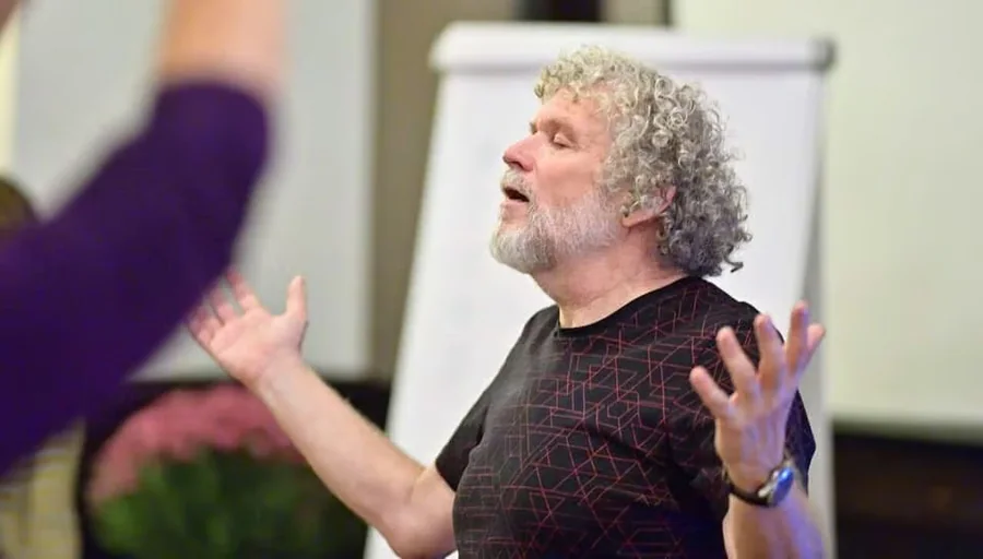 Dan Brulé teaching a breathwork session, arms open mid-instruction